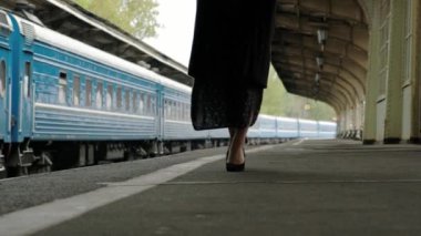 Tren istasyonunda siyah bir ceket çekici orta yaşlı esmer kadın. Ayakkabılar yürüyen bacaklar yakın çekim.