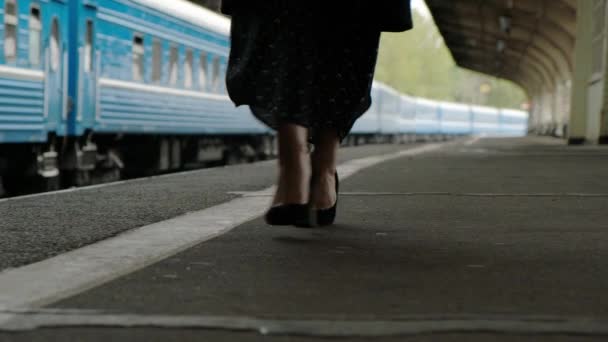 Attraente donna bruna di mezza età con un cappotto nero alla stazione ferroviaria. Primo piano delle gambe che camminano in scarpe . — Video Stock