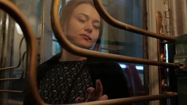 Mulher morena de meia idade atraente em um casaco preto atrás de uma porta vintage de vidro . — Vídeo de Stock