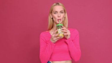 Kırmızı bir T-shirt ve kot pembe arka planda poz çekici genç kadın sarışın.