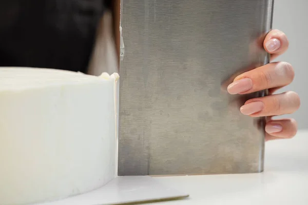 Blanc gâteau cylindrique lisse blanc blanc. Le confiseur crée la forme d'une spatule à pâtisserie . — Photo