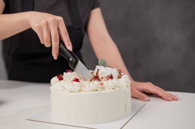 Bir condater büyük bir bıçak ile güzel bir taze dekore beyaz kek keser.