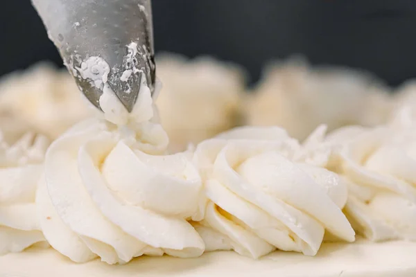 Decorating a white cake with cream from the pastry bag. Macro shot, closeup. — Stock Photo, Image