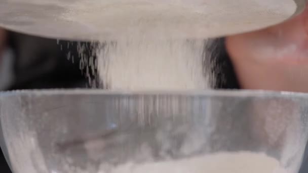 Cozinheiro mulher peneira farinha através de uma peneira em um fundo cinza . — Vídeo de Stock