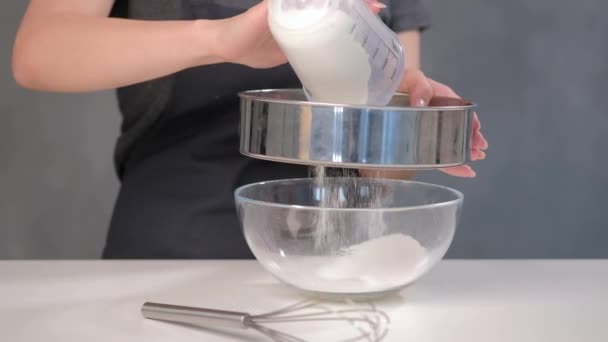 Cook woman sifts flour through a sieve on a gray background. — Stock Video