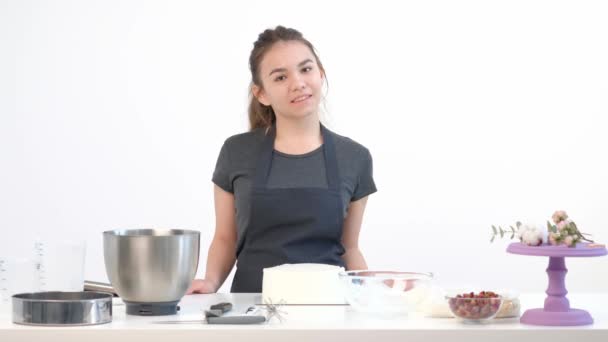 Приваблива брюнетка дівчина випічка шеф-кухаря в фартухах чіпси крем торт в металевій мисці . — стокове відео