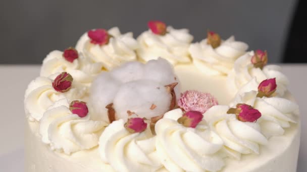 Köchin dekoriert weißen Kuchen mit frischen Blumen. — Stockvideo