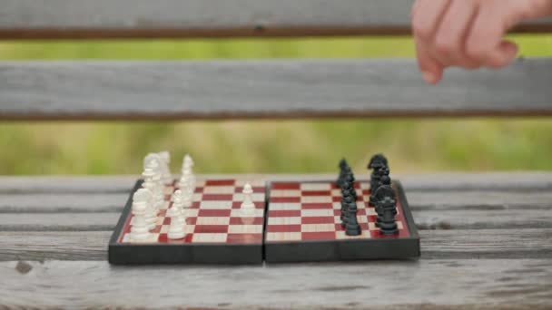 Spelen Schaken buiten. Schaakbord en figuren op de Bank, tegen de achtergrond van groen. Close-up. — Stockvideo