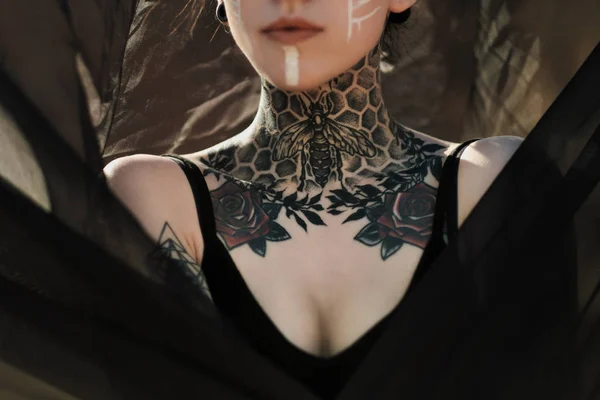 Hermosa mujer sexy en ropa interior negra. El cuerpo está cubierto de muchos tatuajes. Ricitos en la cabeza. Posando contra la carrera de arena y tela negra . —  Fotos de Stock