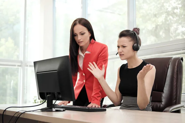 Dvě mladé ženy pracují v jasné kanceláři v počítači. Prodiskutujte pracovní postupy a emocionálně vyřešte problémy. Hlava a podřízený. — Stock fotografie