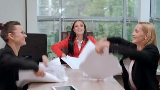 Drie mooie jonge meiden in business suits zitten aan het Bureau. Moe van het werk. Gooi papieren vliegtuigen, en lach. Pauze en rust. — Stockvideo