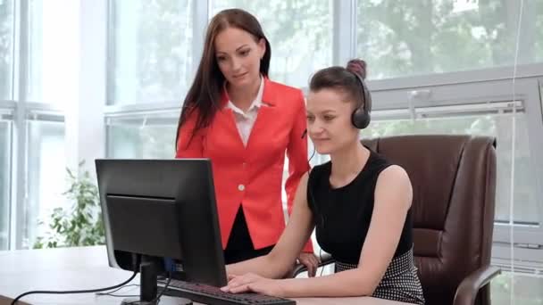 Две молодые женщины работают в светлом офисе за компьютером. Обсудите рабочие процессы и наслаждайтесь успешной сделкой. Глава и подчиненный . — стоковое видео