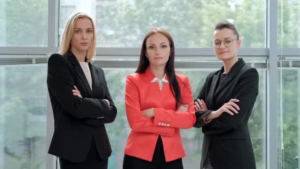 三个穿着西装的年轻漂亮女人在灯光办公室的背景下摆姿势。主管和下属。专业人员和同事工作组. — 图库视频影像