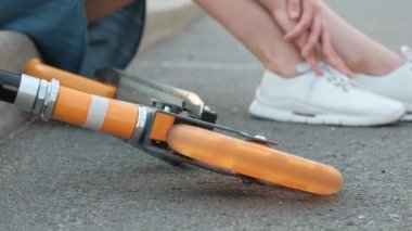 Kot elbise ve beyaz spor ayakkabıları boyalı saçlı çekici genç kadın kaldırımda oturur ve dayanır.