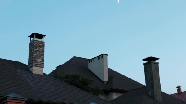 O telhado de uma casa privada ao entardecer. No céu está a lua crescente . — Vídeo de Stock
