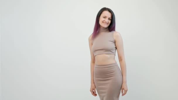 Attractive young woman with dyed hair in a beige crochet top and skirt posing on a white background. — Stock Video