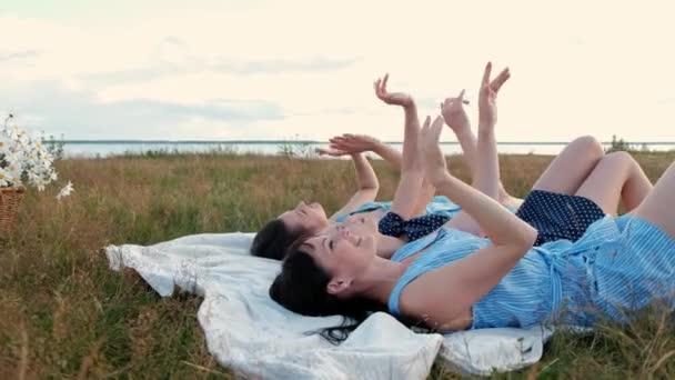 Tres mujeres jóvenes y atractivas están tumbadas en un tartán y mirando al cielo. Ríete y señala, baila. Descanso novias al aire libre naturaleza . — Vídeos de Stock