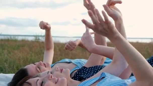 Három fiatal vonzó nők feküdt egy kockás, és nézte az eget. Nevessen és pont fel, táncolni. Pihenés barátnők szabadban természet. — Stock videók