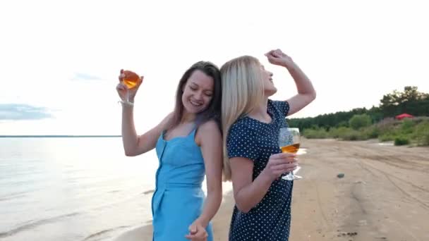 Three young attractive women, in blue dresses are walking along the seashore. Girlfriends communicate, laugh and drink wine. — Stock Video