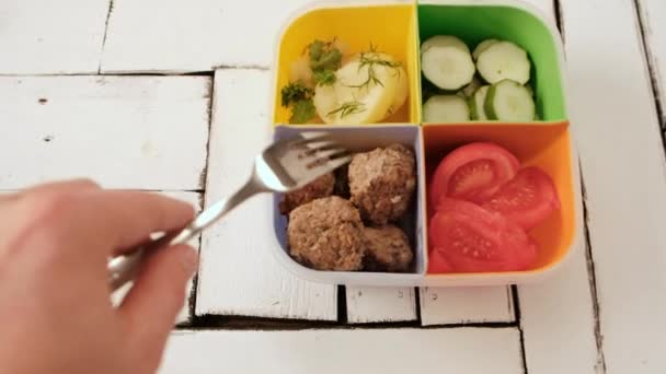 Lunch låda med celler. grönsaker, gurkor och tomater, kokt potatis och köttfärsbiffar. — Stockvideo