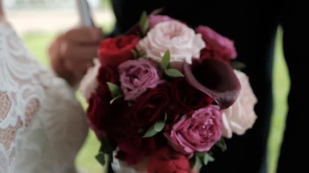 Bouquet de mariée rouge foncé dans les mains. Pivoines et callas aux gouttes de pluie . — Video