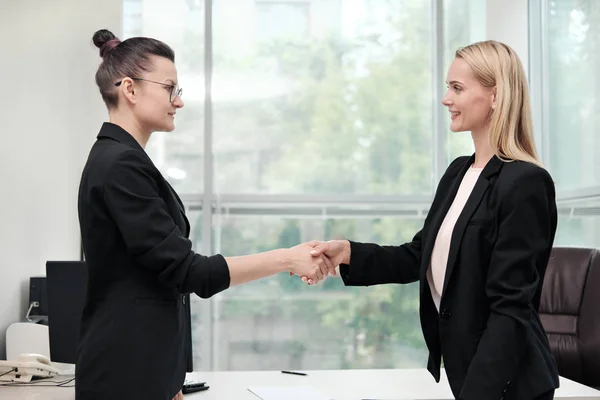 Twee mooie jonge vrouwen in business suits schudden de handen en glimlach. Een vacature inhuren. Ondertekening van de overeenkomst. Vrouwen op het werk. — Stockfoto