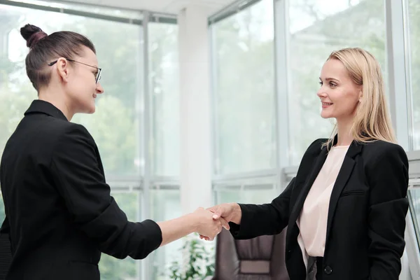 Twee mooie jonge vrouwen in business suits schudden de handen en glimlach. Een vacature inhuren. Ondertekening van de overeenkomst. Vrouwen op het werk. — Stockfoto