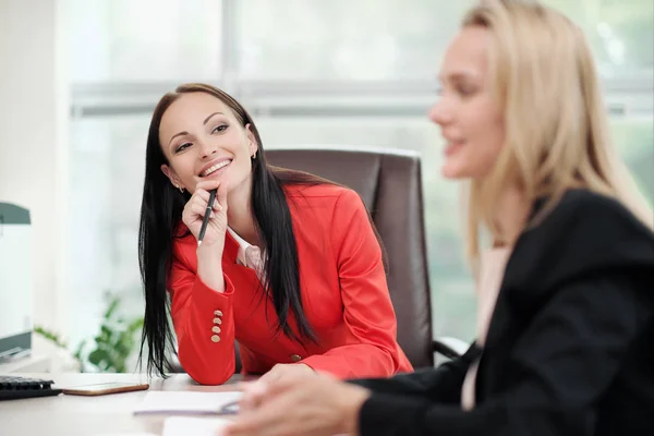 Three young attractive women in business suits are sitting at a desk and discussing workflows. Head and subordinates. Working team of professionals and colleagues. — Stock Photo, Image