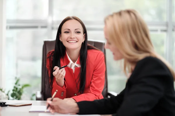 Drie jonge aantrekkelijke vrouwen in business suits zitten aan een bureau en bespreken workflows. Hoofd en ondergeschivelde. Werk team van professionals en collega's. — Stockfoto