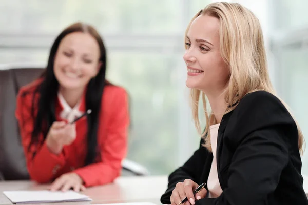 Tres mujeres jóvenes y atractivas en trajes de trabajo están sentadas en un escritorio y discutiendo los flujos de trabajo. Cabeza y subordinados. Equipo de trabajo de profesionales y colegas . — Foto de Stock