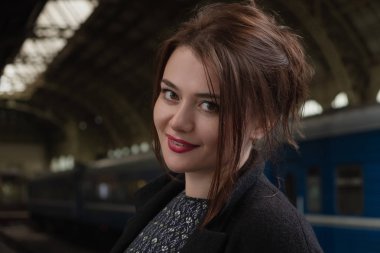 Çekici genç kadın Millenial siyah giysiler ve bir şapka ve gözlük tren yanındaki tren istasyonunda. Ciddi bir görünüm, treni bekliyor..