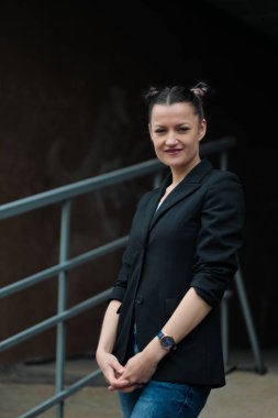 Siyah ceket ve mavi kot Genç çekici kadın binanın arka plana karşı açık poz.