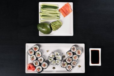 Kırmızı balık ve zencefil ile rulo seti. Masa ayarı. Siyah arka plan.