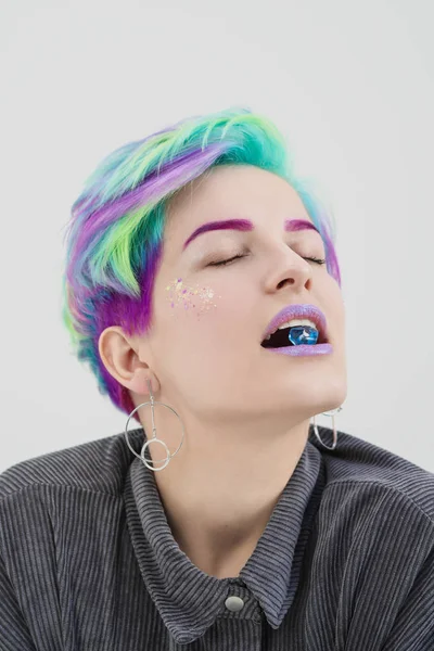 A young woman with short pixie bob haircut and dyed hair, holds in the mouth and in the hands gemstones and jewels. — Stock Photo, Image