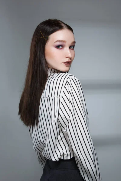 Young beautiful female fashion model in a business stylish suit on a rerom background. Holds a stack of papers and a pen. — Stock Photo, Image