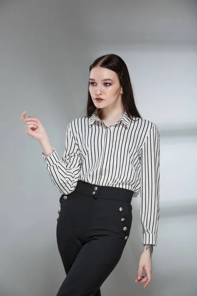 Junge schöne weibliche Mode-Modell in einem Business-stilvollen Anzug auf einem Wiederholungshintergrund. hält einen Stapel Papiere und einen Stift. — Stockfoto