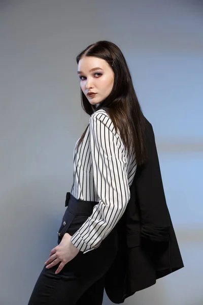 Jonge mooie vrouwelijke mode model in een Business stijlvolle pak op een rerom achtergrond. Bevat een stapel papier en een pen. — Stockfoto