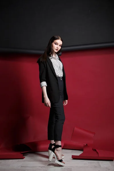 Молода красива жіноча модель моди в діловому стильному костюмі на червоно-чорному тлі . — стокове фото