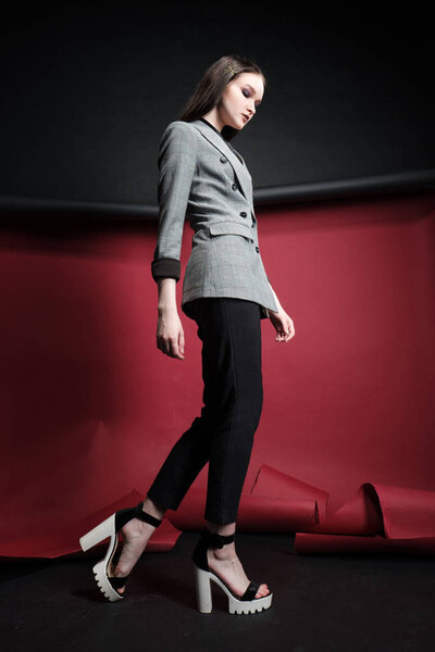 Young beautiful female fashion model in a business stylish suit on a red and black background.