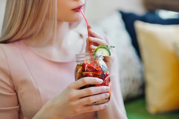 Jeune belle fille blonde dans une robe rose s'assoit à une table de café, boit de la limonade dans un bocal en verre . — Photo