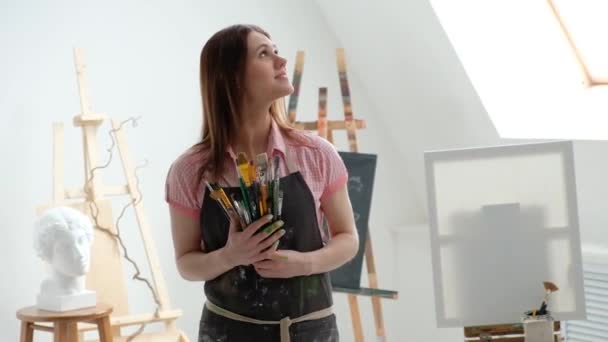 Młoda piękna kobieta malarz wśród szwaczka i płótna w jasnym studiu. — Wideo stockowe
