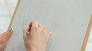 Parlak bir stüdyoda şere ve tuvaller arasında genç güzel kadın ressam. İlham ve hobi.