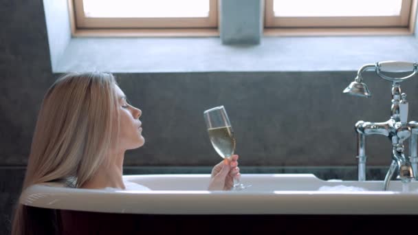 Όμορφη ξανθιά γυναίκα βρίσκεται σε ένα μπάνιο με αφρό και χαλαρώνει. — Αρχείο Βίντεο