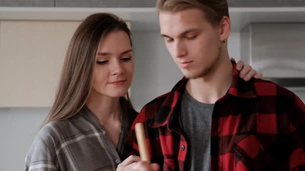 Jovem casal bonito em camisas xadrez estão cozinhando em casa na cozinha . — Vídeo de Stock