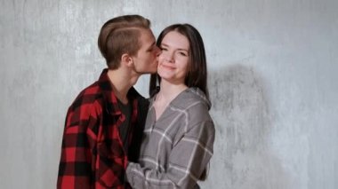 Genç güzel çift, erkek ve kadın, şefkatle evin gri duvara karşı kucaklayan.
