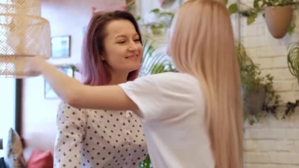 Duas meninas bonitas jovens amigos se encontram e abraçam em um café . — Vídeo de Stock