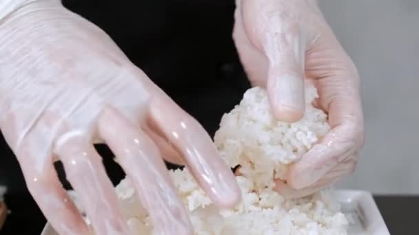 O jovem chef de sushi masculino prepara rolos de sushi japoneses de arroz, salmão, abacate e nori. Restaurante cozinha . — Vídeo de Stock