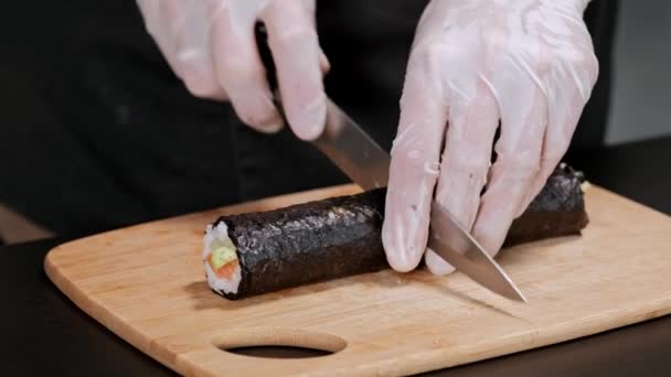 Mladý suši šéfkuchař připravuje japonské Suši z rýže, lososa, avokáda a nori. Restaurace kuchyně, šatní ruce. — Stock video