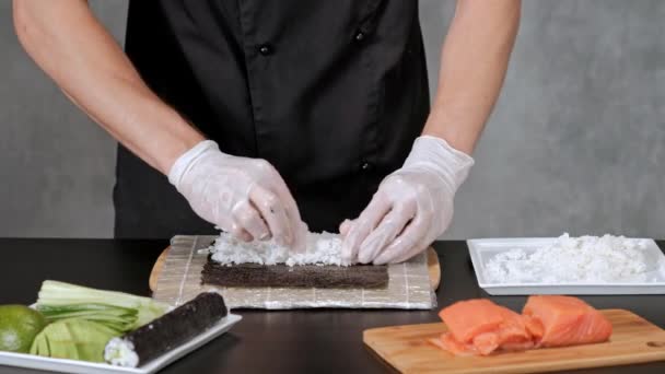 Mladý suši šéfkuchař připravuje japonské Suši z rýže, lososa, avokáda a nori. Restaurace kuchyně. — Stock video