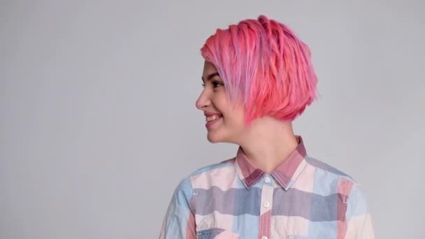 Joven hermosa chica con un corte de pelo corto pixie bob. Colorante de color de pelo, color rosa rojo. Camisa en un sótano, estilo casual . — Vídeo de stock